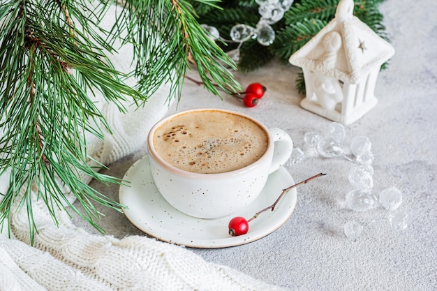 Uma xícara de cappuccino (lat) sobre um fundo claro perto de uma árvore de Natal e decorações.