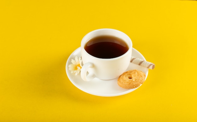 Uma xícara de chá com biscoito em um amarelo