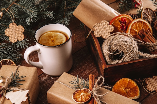 Uma xícara de chá com limão e materiais ecológicos para embrulhar presentes de ano novo em uma mesa de madeira