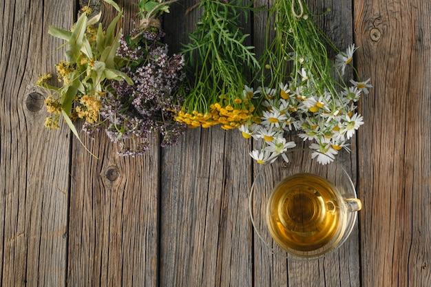 Uma xícara de chá de camomila em um copo de vidro e um buquê de flores do campo de verão