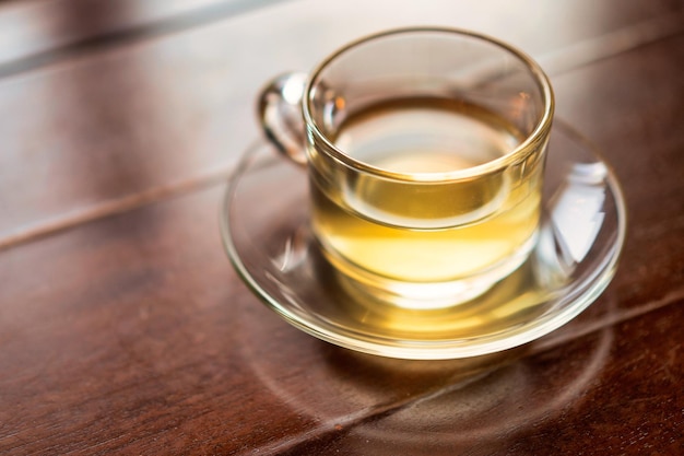Uma xícara de chá está sobre uma mesa com um pires e um copo de chá.