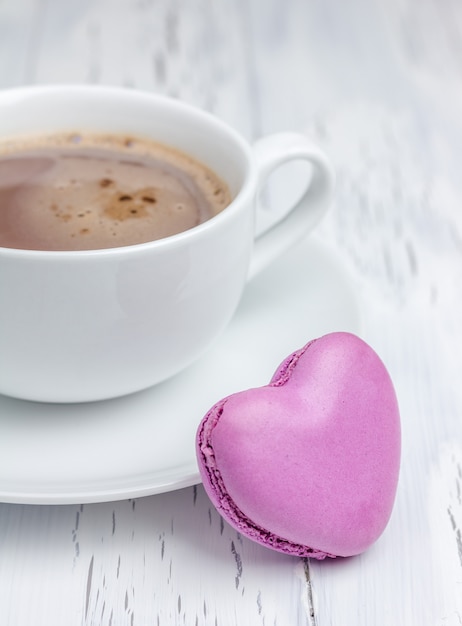 Uma xícara de chocolate quente com um macaron em forma de coração