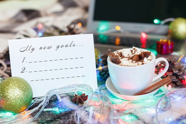 Uma xícara de chocolate quente e marshmallows na decoração de natal. lista de metas de ano novo.