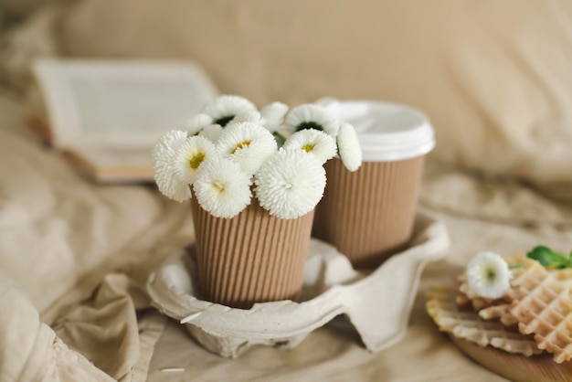 Uma xícara de flores em uma bandeja com um livro sobre a mesa.