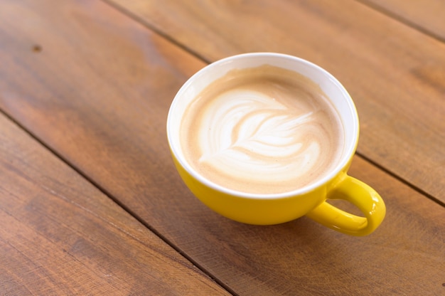 Uma xícara de latte art na mesa de madeira