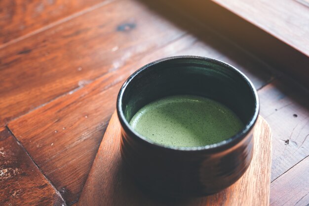 Uma xícara de matcha quente com leite no chão de madeira