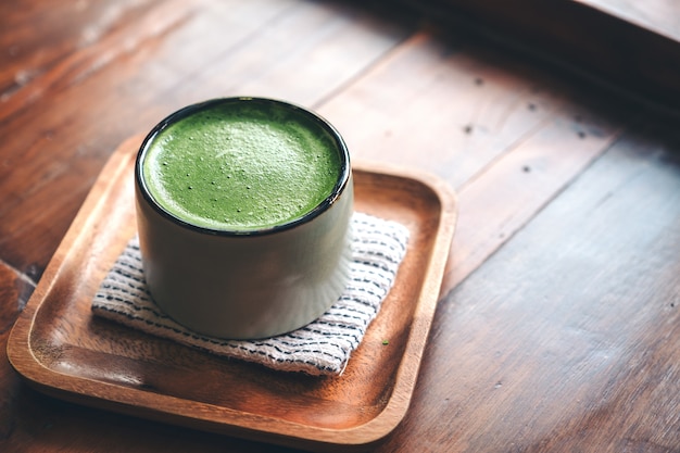 Uma xícara de matcha quente com leite no chão de madeira