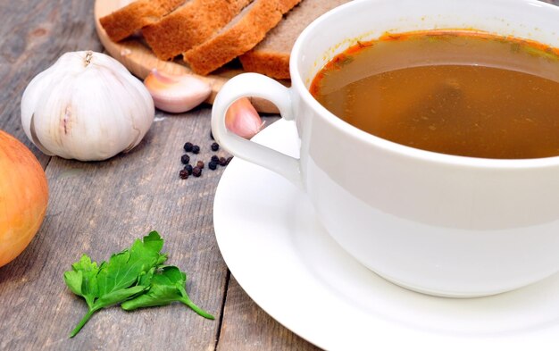 Uma xícara de sopa com alho em uma mesa de madeira