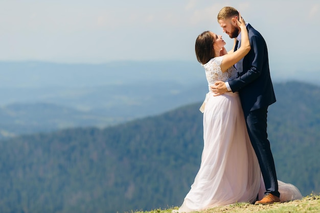 Umarmen Sie das Brautpaar mit Leidenschaft auf dem Berg mit einem großartigen Aussichtsprofil von Brautpaaren, die sich gegenseitig ansehen