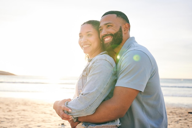 Umarmen Sie Strand und Paar mit Liebe, Sonnenuntergang und Ehe mit Glück, Sommerurlaub und Beziehung. Romantik, glücklicher Mann und Frau umarmen Urlaub am Meer und Beziehung mit einem Lächeln und Reisen