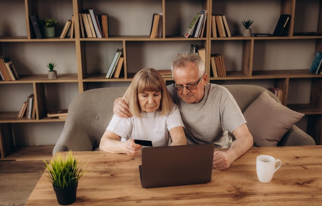 Umarmtes reifes Paar, das zu Hause auf dem Laptop im Internet surft