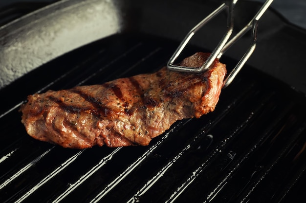 Umdrehen von gebratenem Steak auf Grillpfanne in der Nähe