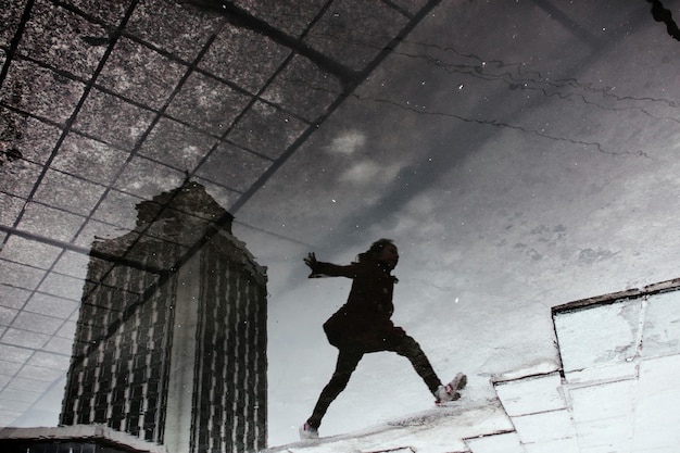 Foto umgekehrtes bild eines mannes, der auf einem fußweg in der stadt durch eine pfütze springt