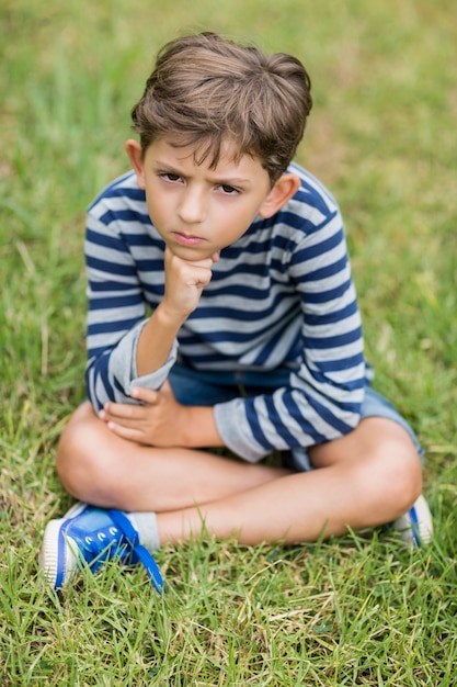 Umgekippter Junge, der auf Gras sitzt