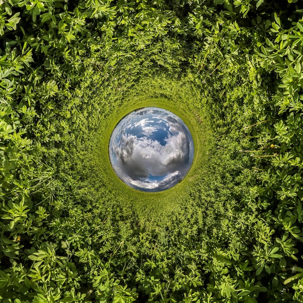 Umkehrung des blauen winzigen Planeten Transformation des sphärischen Panoramas 360 Grad Sphärische abstrakte Luftaufnahme auf der grünen Wiese mit fantastischen schönen Wolken Krümmung des Weltraums