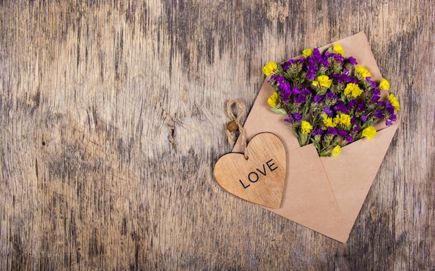 Umschlag mit Blumen auf Holztisch