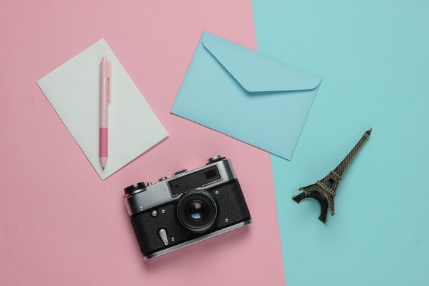 Umschlag mit Brief, Retro-Kamera auf rosa blauem Pastellhintergrund. Draufsicht. Reisekonzept. Pariser Reise