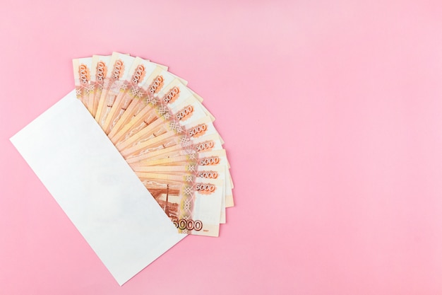 Umschlag mit russischem Geld auf einem rosa Hintergrund
