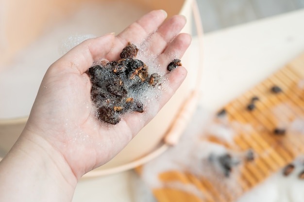 Umweltfreundliches Naturwaschmittel - Waschnüsse und Waschbrett. Kein Verlust. Die Hand einer Frau hält Waschnüsse über einem Waschbecken. Handwäsche.