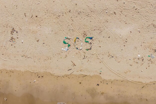 Foto umweltproblem ökologiekonzept plastik am strand mit sos-schriftzug verschütteter müll am strand