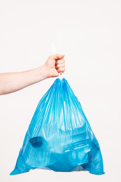 Umweltschutz. Mannhand hält blaue Plastiktüte voll mit Müll, auf weißem Hintergrund