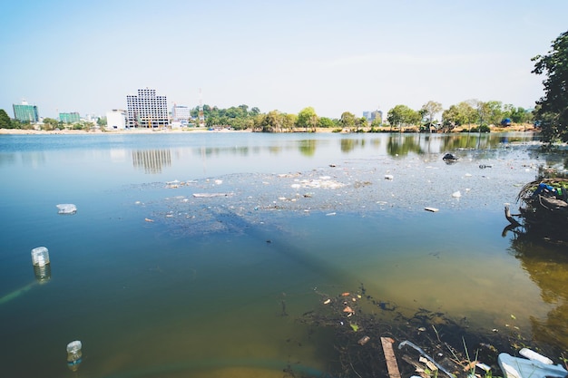 Umweltverschmutzung in der Stadt menschliche Abfälle Müll im Teich auf dem Hintergrund der Stadthäuser