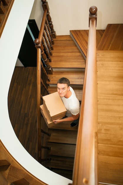 Umzug. Junger Mann mit Kartons auf einer Treppe.