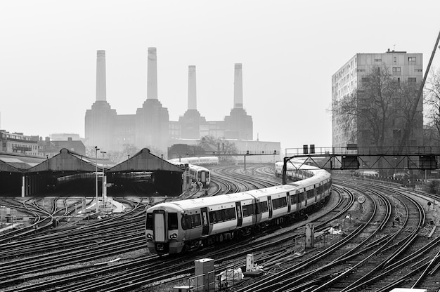 Umzug von Nahverkehrszügen und Eisenbahnschienen in London mit dem Kraftwerk Battersea hinter dem Nebel.