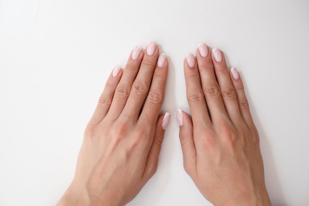 Uñas de los dedos de la mano femenina con manicura después del procedimiento de salón de uñas