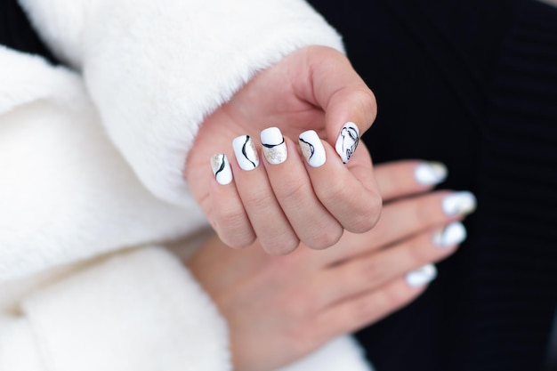 Las uñas de una mujer con esmalte de uñas blanco y negro.