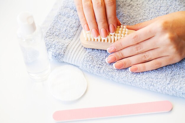 Uñas de mujer hermosa con manicura francesa en estudio de belleza