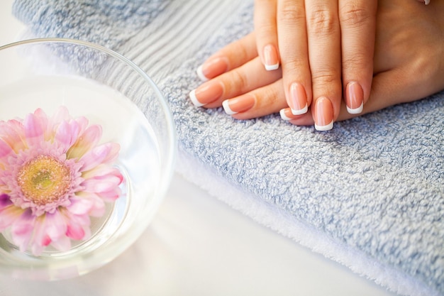 Uñas de mujer hermosa con manicura francesa, en estudio de belleza.