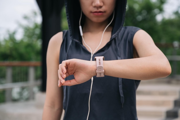 Unbekannte schöne asiatische Frau, die nach dem Joggen die Smartwatch überprüft