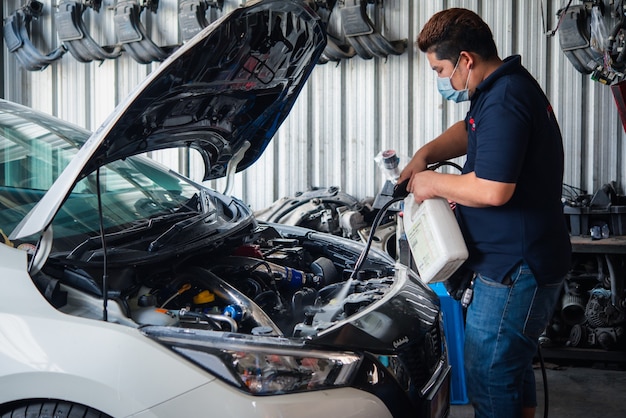 Unbekannter Automechaniker oder Servicemann, der den Automotor nach Überprüfung eines Automotors reinigt