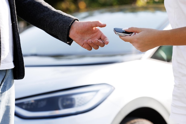 Foto unbekannter autoverkäufer und ein mann, der ein fahrzeug gekauft hat, schütteln sich die hände und geben dem neuen besitzer den schlüssel