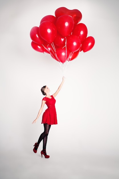 Unbeschwerte junge Frau mit roten Luftballons