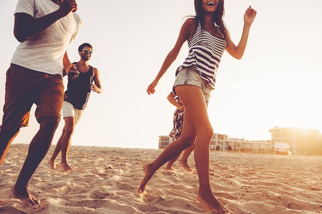 Unbeschwerter Lauf. Gruppe junger fröhlicher Leute, die am Strand entlang laufen und glücklich aussehen looking