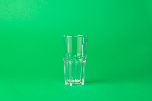 Foto und leeres facettiertes glas auf grünem hintergrund