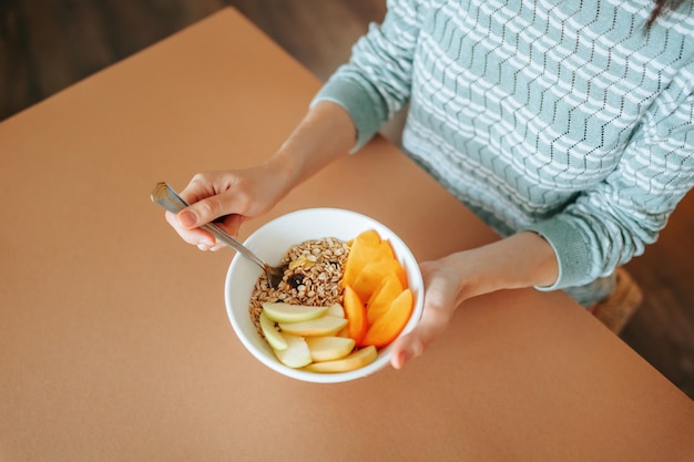 Unerkennbare Draufsicht auf einen Teller mit einem Diät-Frucht-Müsli-Frühstück in einer weiblichen Hand aus nächster Nähe