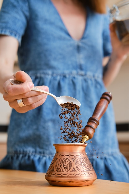 Unerkennbare Frau, die türkischen Kaffee macht, Groung-Kaffee in Cazve gießt (Fokus auf Vordergrund)