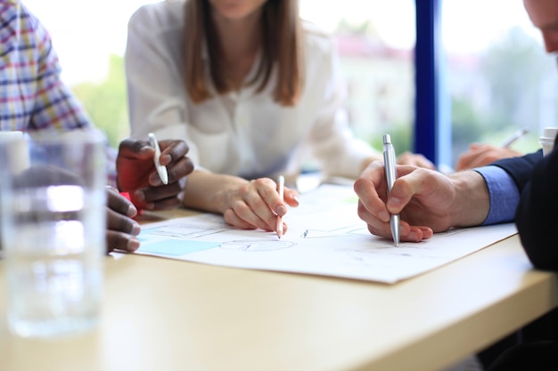 Unerkennbare Geschäftsperson, die Grafiken analysiert und Notizen macht