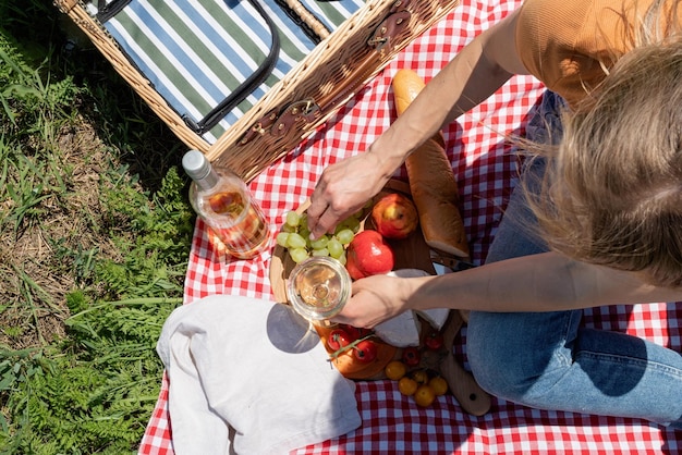 Unerkennbare junge Frau im Park draußen an sonnigen Tagen, die im Sommer träumt und Wein trinkt