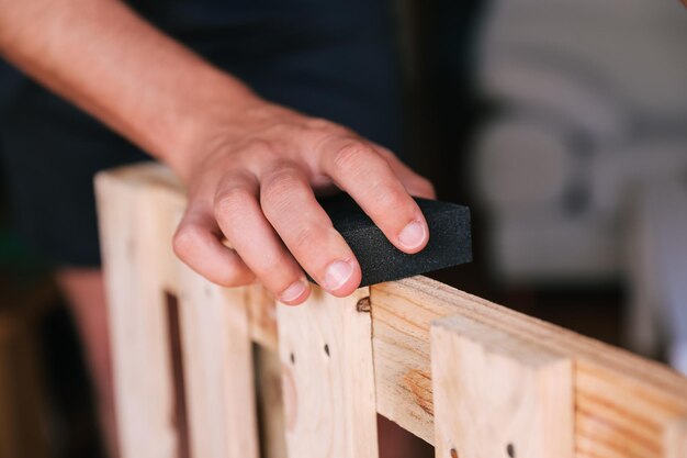 Foto unerkennbare männerhand schleift eine palette hausrenovierung