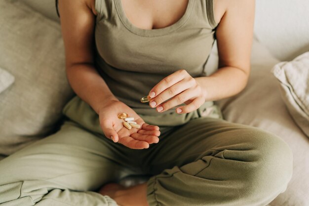 Unerkennbare weiße Frau mit Omega-3-Fischölkapseln in den Händen und Vitaminen