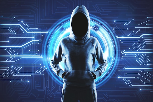 Unerkennbarer Hacker im Kapuzenpullover steht auf abstraktem Schaltkreishintergrund Hardware und kriminelles Konzept