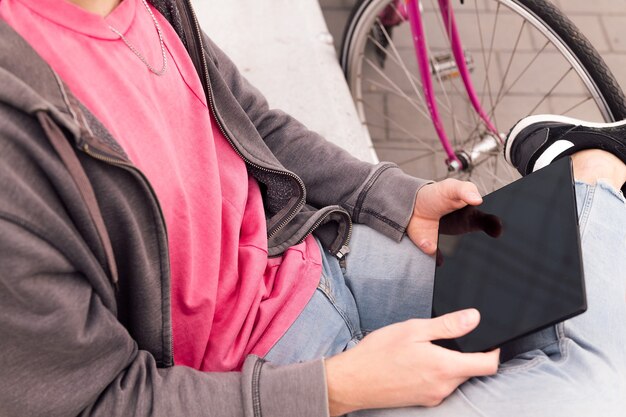 Unerkennbarer junger Mann mit Tablet im Freien