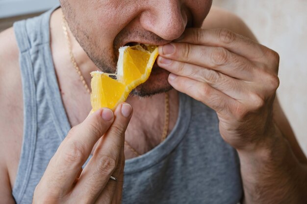 Unerkennbarer Mann mittleren Alters isst eine Orangenscheibe in Nahaufnahme