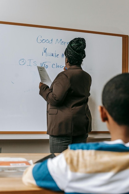 Unerkennbarer schwarzer Lehrer, der im Klassenzimmer auf eine Tafel schreibt