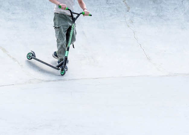 Unerkennbares Kind mit Roller in einem Skatepark an einem sonnigen Sommertag