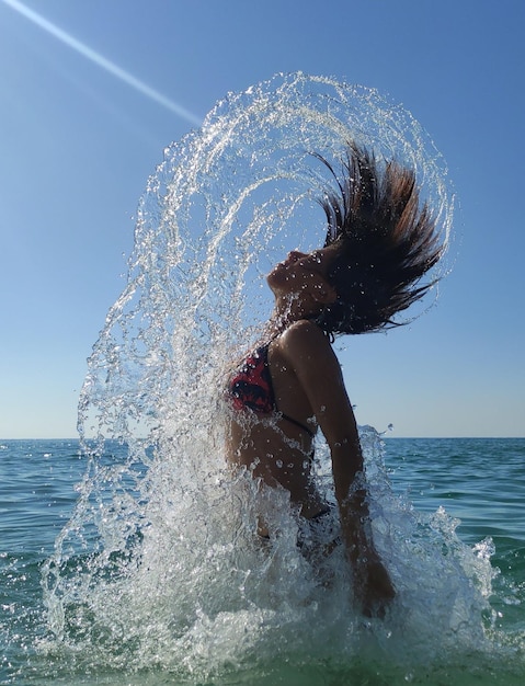 Foto unerkennbares mädchen kommt aus dem meer wasser wasserbogen